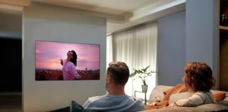 A man and a woman enjoying the state-of-the-art picture quality that comes with LG OLED TV GX on their cozy living room sofa.